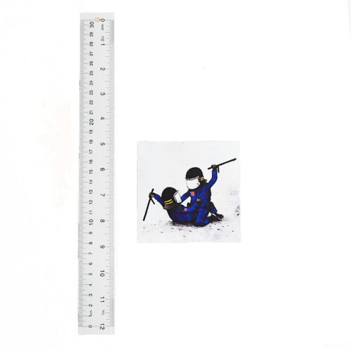dran riot police sticker next to ruler for size scale