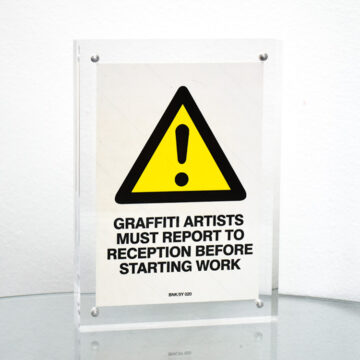 banksy graffiti artists must report to reception sticker in frame