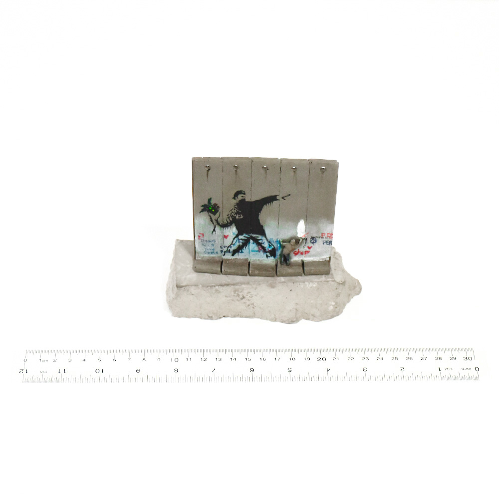 banksy walled off hotel flower thrower wall sculpture on base next to ruler