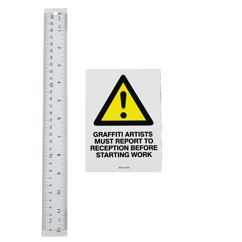 banksy graffiti artists must report to reception sticker next to ruler