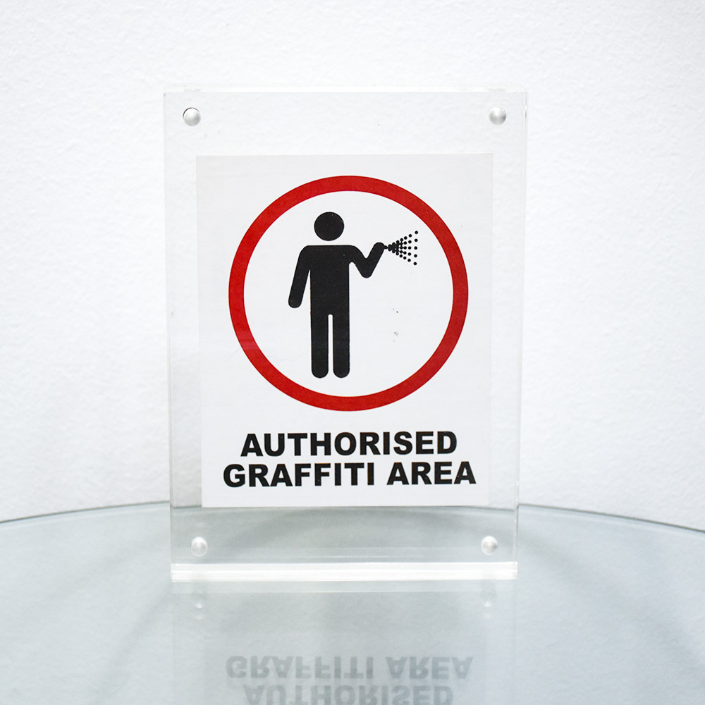banksy authorised graffiti area sticker framed on table